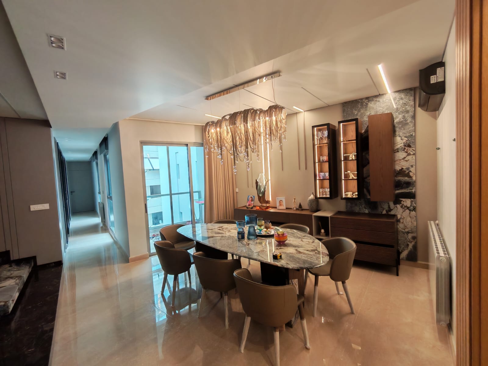Dining area with marble-top table, statement chandelier and wood display units